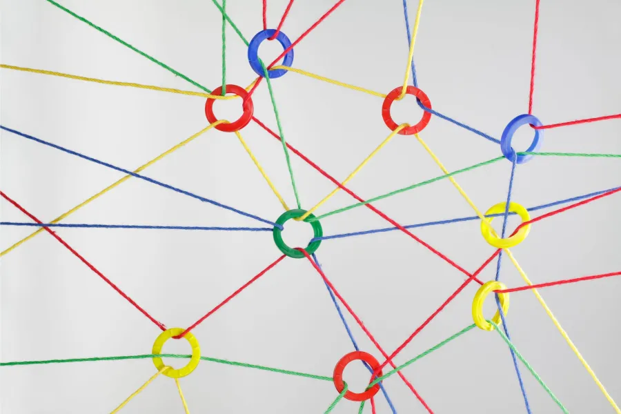 Multicolored strings tied together with different colored rings in red, blue, green or yellow colors making a web.