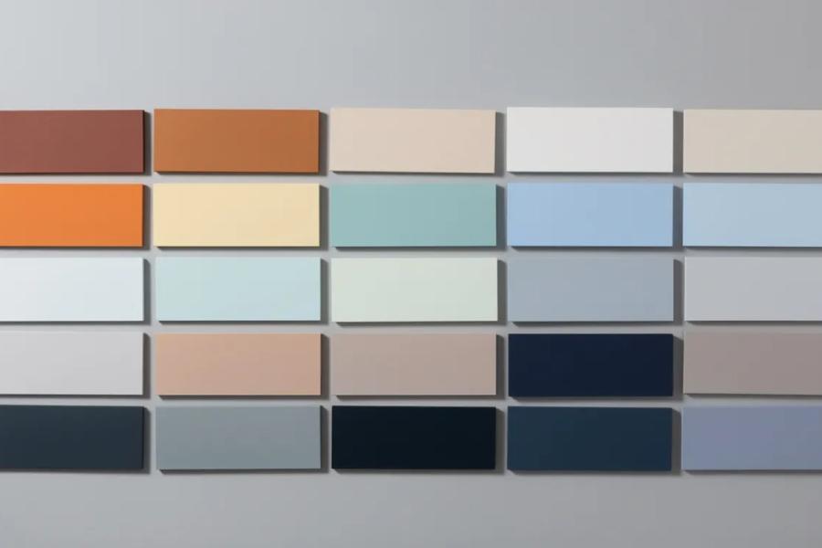 Grid of rectangular colour swatches on a grey wall, ranging from terracotta and orange through soft blues and neutrals to navy
