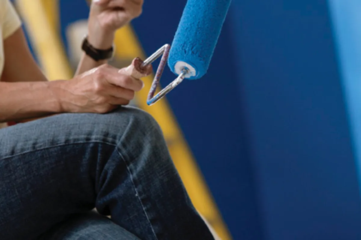 Hand with a roller painting blue paint.
